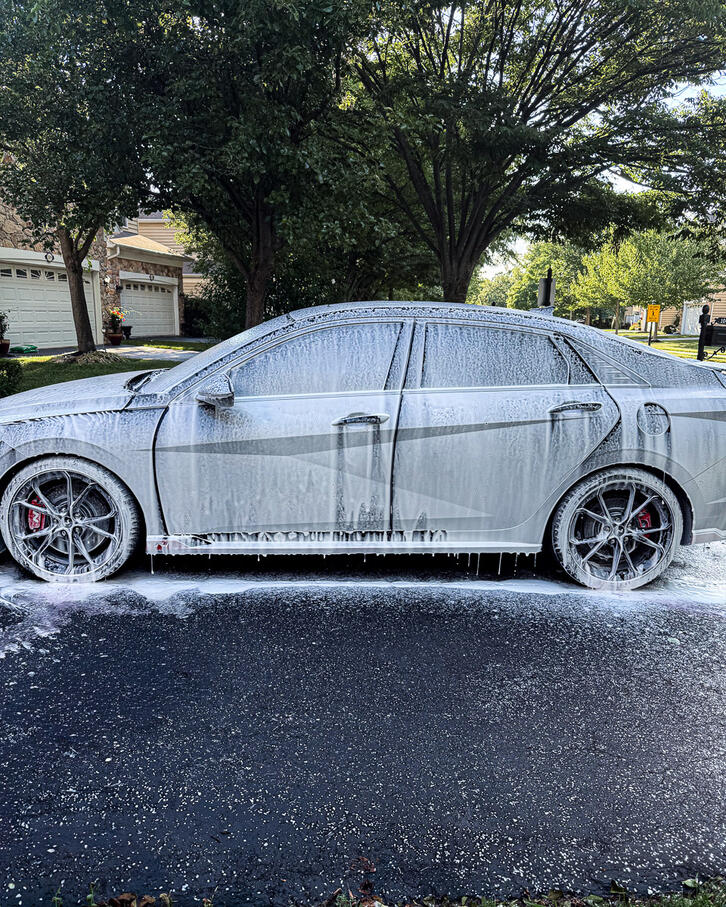 Black sedan vehicle completely covered in thick professional snow foam pre-wash in Oaks PA